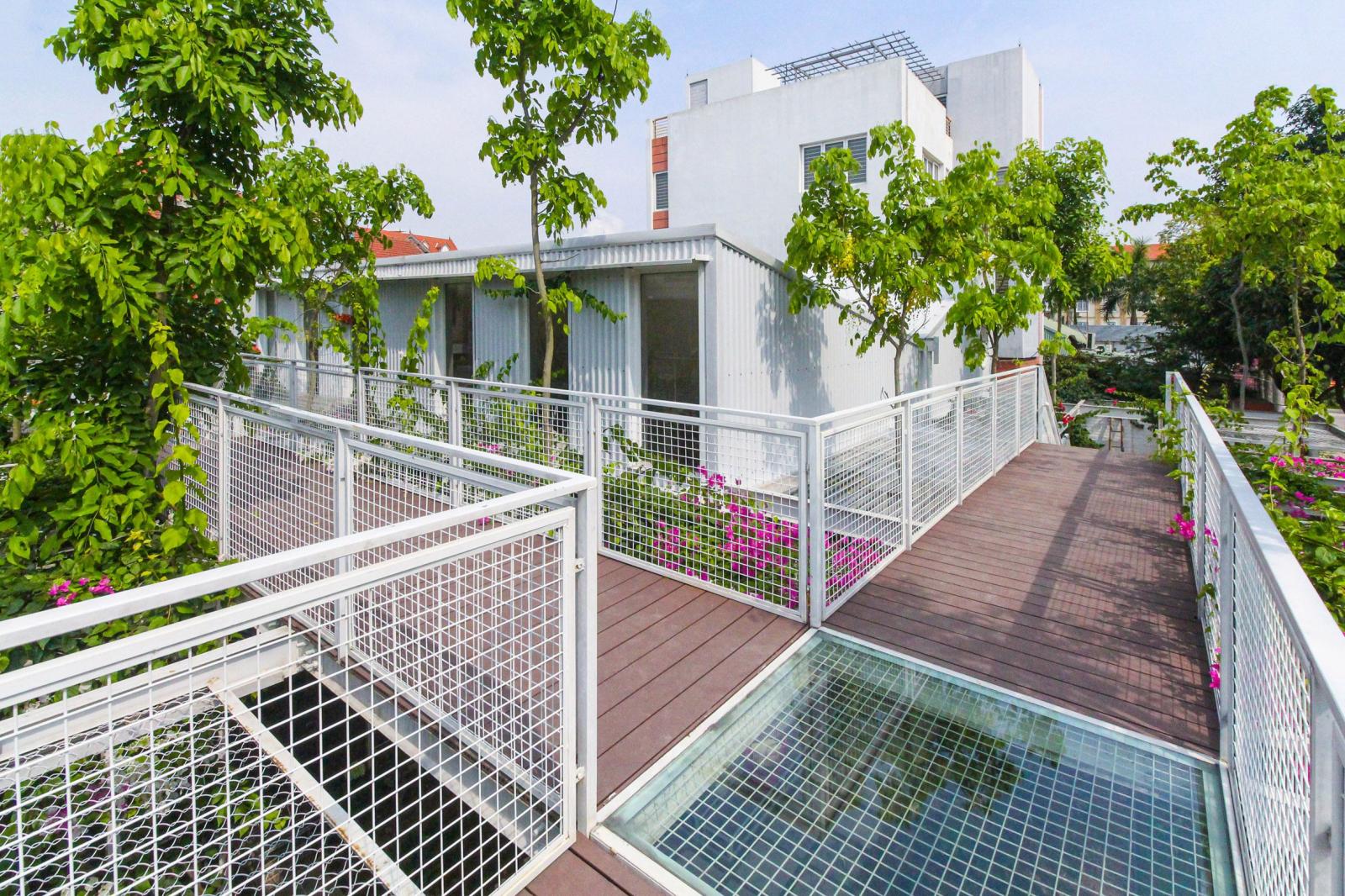 Ba cầu thang kim loại dẫn l&ecirc;n lối đi bằng gỗ ở tr&ecirc;n, c&oacute; dạng h&igrave;nh chữ T cắt ngang giữa v&agrave; trước 2 d&atilde;y ph&ograve;ng học b&ecirc;n dưới. Lan can được ho&agrave;n thiện bằng lưới kim loại kh&aacute;c.