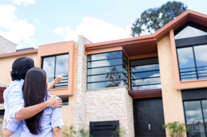 2 vợ chồng trẻ đứng trước ngôi nhà