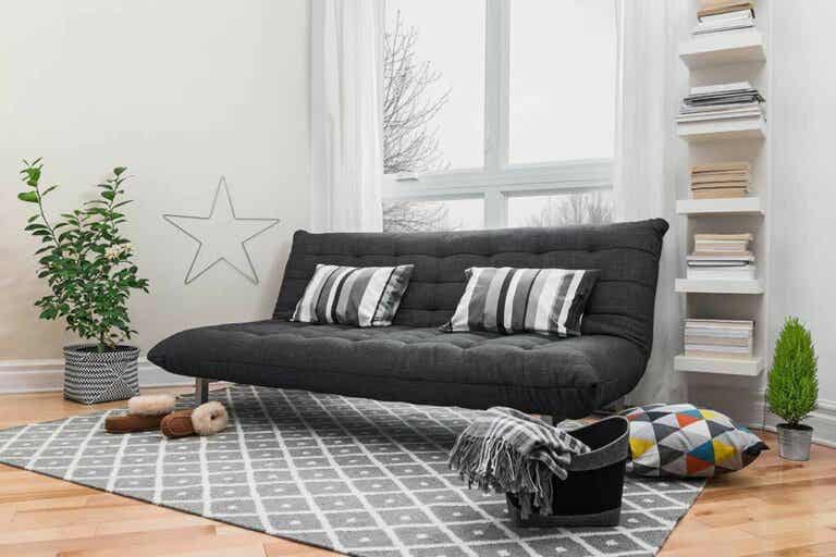 ghế sofa giường màu đen đặt trong phòng khách, cạnh cửa sổ kính