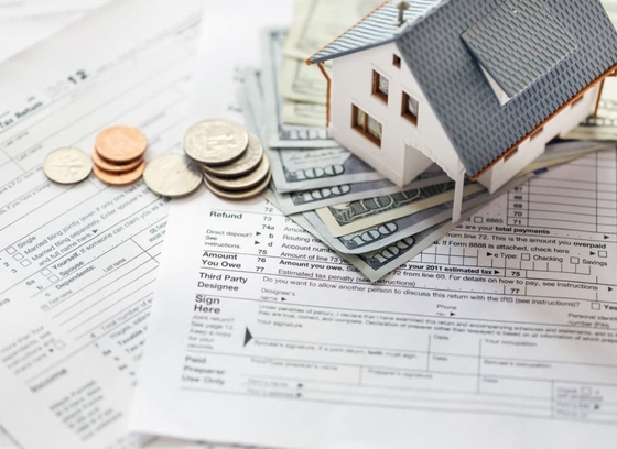 m&ocirc; h&igrave;nh ngồi nh&agrave; đặt tr&ecirc;n tiền USD, tiền xu minh họa cho lệ ph&iacute; trước bạ nh&agrave; đất