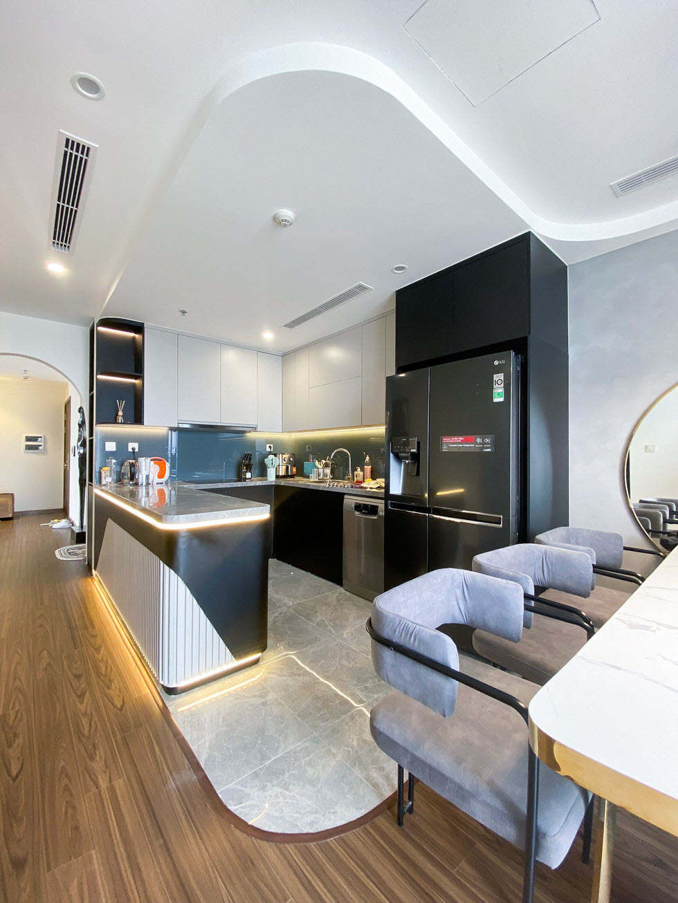 Liền kề phòng ăn là khu bếp nấu hiện đại, đủ đầy tiện ích. Hệ đèn LED giúp làm nổi bật bảo bếp và hệ tủ kịch trần.