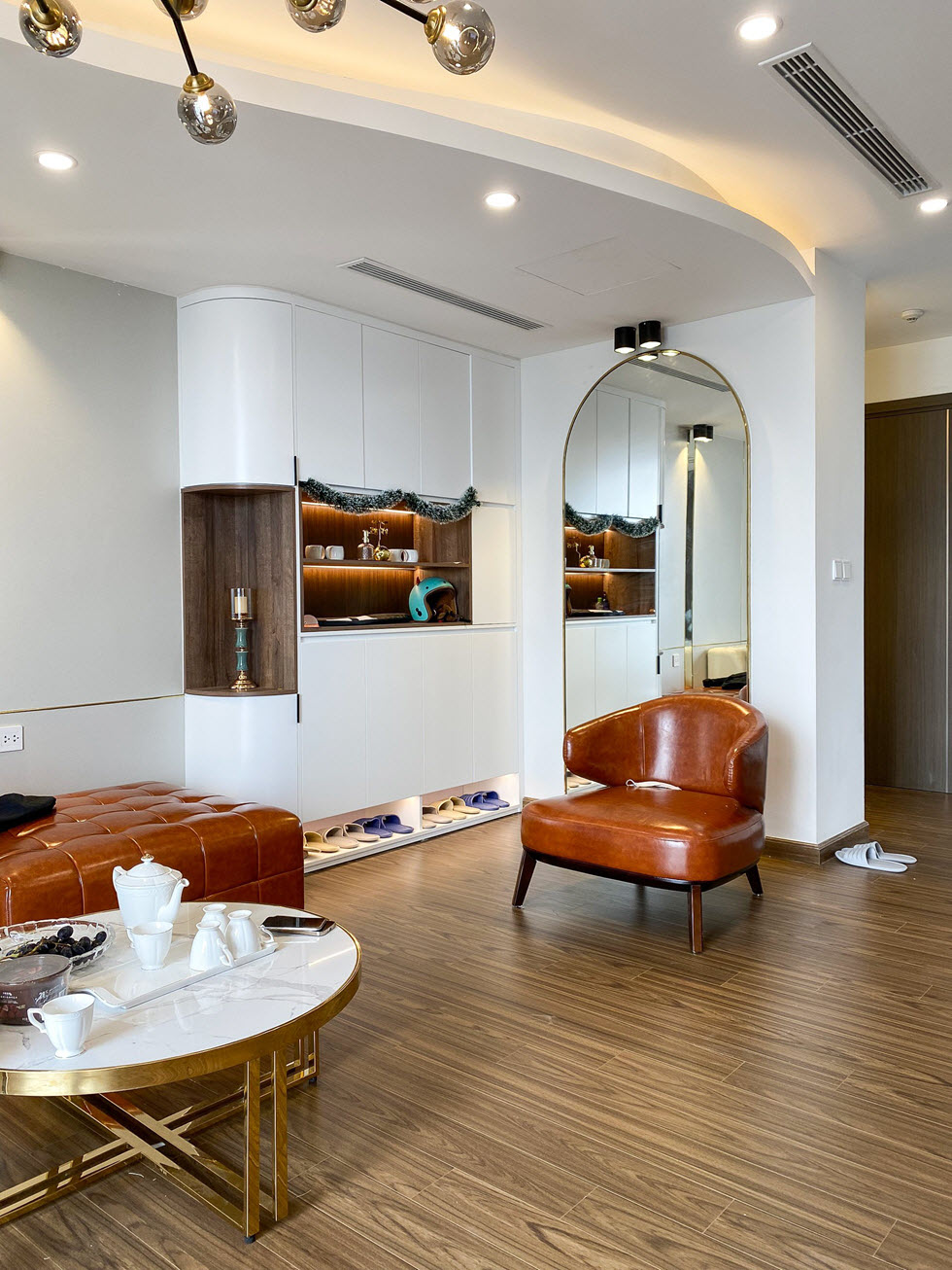 Khu vực lối vào căn hộ 150m2 gây ấn tượng bởi gương lớn gắn tường và hệ tủ kịch trần tông màu trắng tinh khôi.