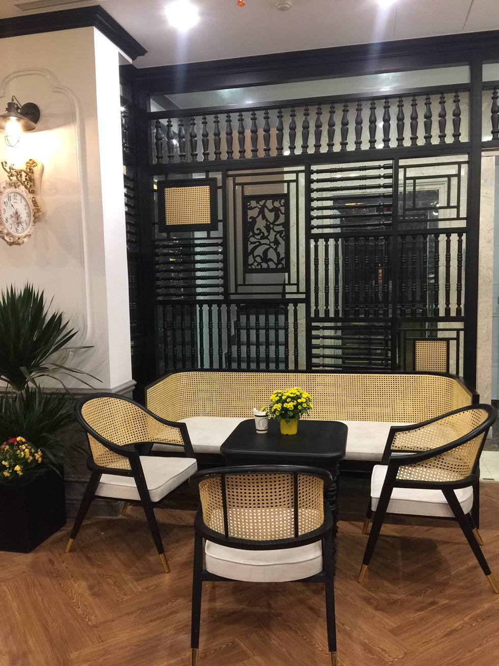 Bộ bàn ghế với phần tựa lưng bằng mây mềm mại, hài hòa cùng vách lam đậm chất Đông Dương, mang lại trải nghiệm thú vị cho thực khách.