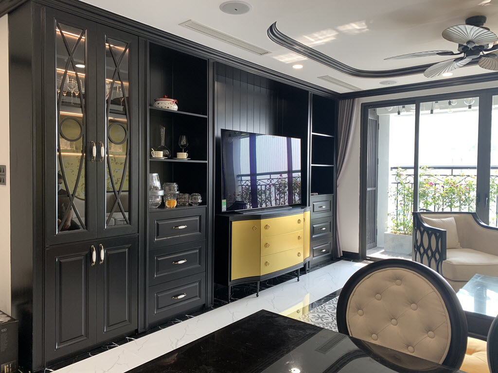 Kệ tivi v&agrave; tủ rượu được đ&oacute;ng liền khối, tạo th&agrave;nh mảng trang tr&iacute; liền mạch cho ph&ograve;ng kh&aacute;ch. Tủ ngăn k&eacute;o sơn v&agrave;ng theo phong c&aacute;ch Đ&ocirc;ng Dương tạo điểm nhấn h&uacute;t mắt.