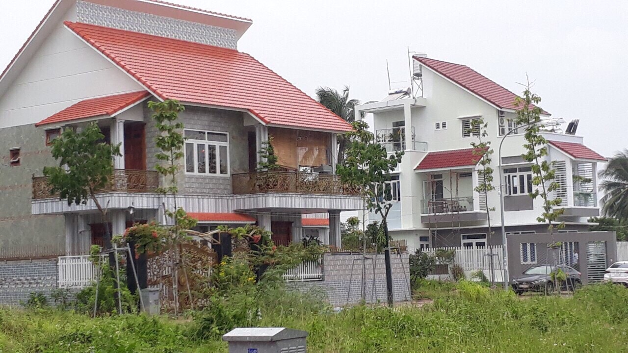 hình ảnh biệt thự mái ngói đỏ, cạnh đó là đất trống cỏ mọc xanh tốt minh họa cho mua đất không chính chủ