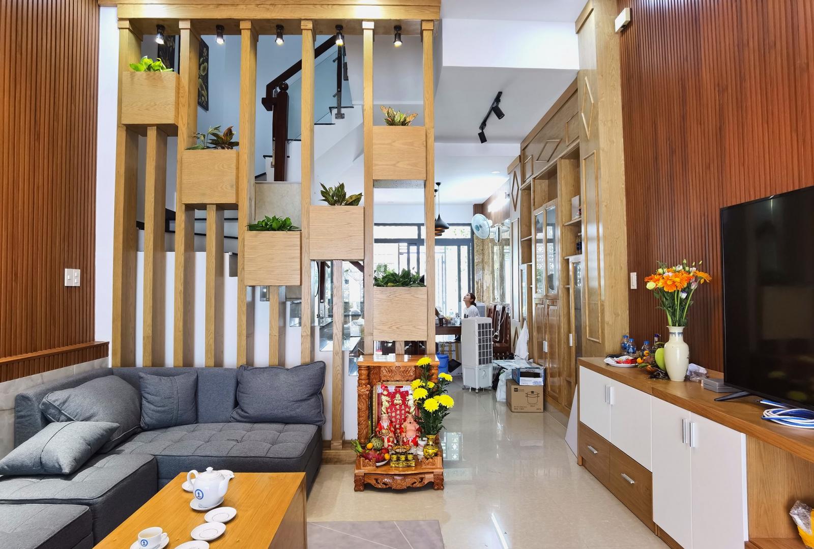Phòng khách có thiết kế đơn giản hiện đại với điểm nhấn là vách lam trang trí, giúp che chắn khu vực cầu thang bên trong.