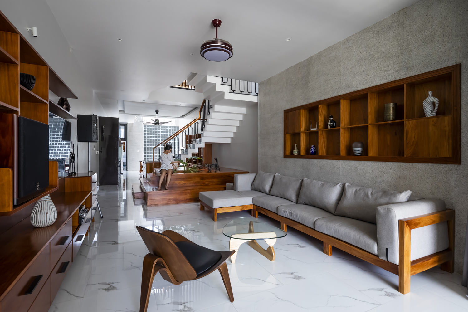 ph&ograve;ng kh&aacute;ch nh&agrave; ống với sofa gỗ l&oacute;t đệm m&agrave;u x&aacute;m trắng, hệ tủ gỗ lưu trữ gắn tường