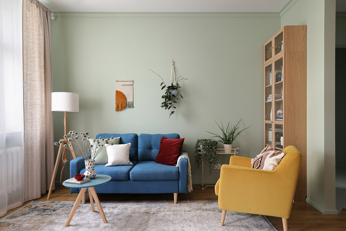 ph&ograve;ng kh&aacute;ch với sofa xanh dương, ghế b&agrave;nh m&agrave;u v&agrave;ng, gối tựa m&agrave;u đỏ nổi bật
