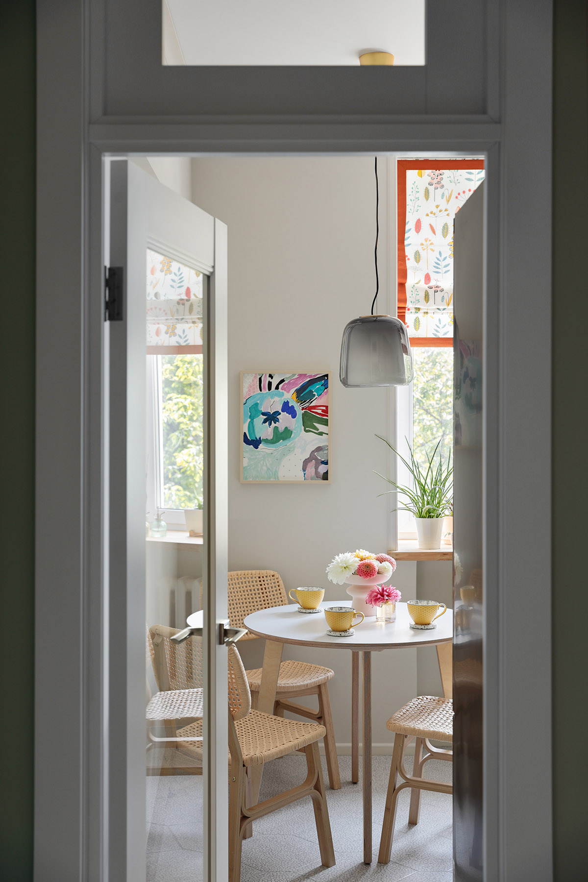 B&agrave;n ăn nhỏ với ghế m&acirc;y tre đan lấp đầy phần c&ograve;n lại của nh&agrave; bếp. Căn ph&ograve;ng ph&acirc;n t&aacute;ch với kh&ocirc;ng gian b&ecirc;n ngo&agrave;i bằng cửa k&iacute;nh hiện đại.