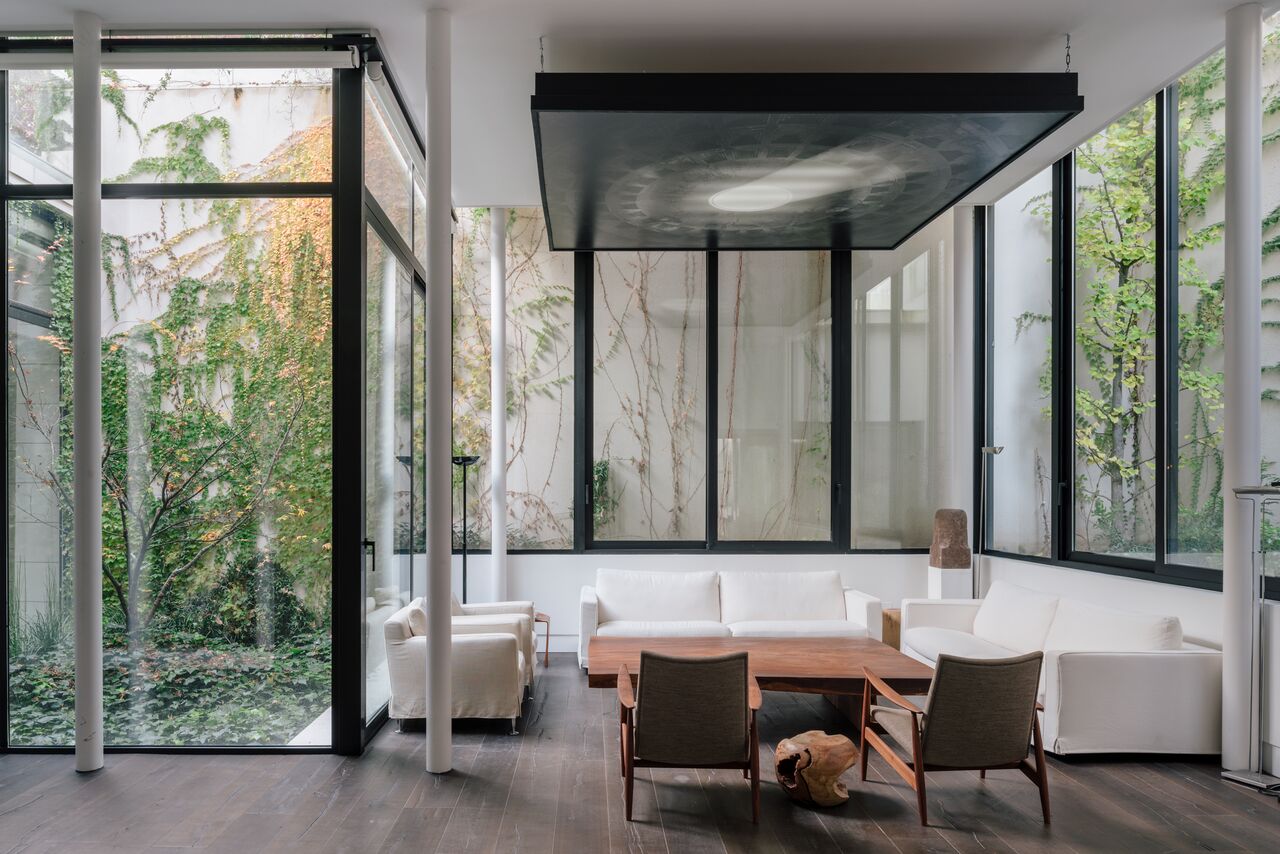 Khoảng s&acirc;n h&igrave;nh chữ U l&agrave;m cho ph&ograve;ng kh&aacute;ch n&agrave;y được bao bọc bởi thi&ecirc;n nhi&ecirc;n ở ba mặt. Khung cửa sổ m&agrave;u đen tương phản mạnh mẽ với khung cảnh xanh m&aacute;t.