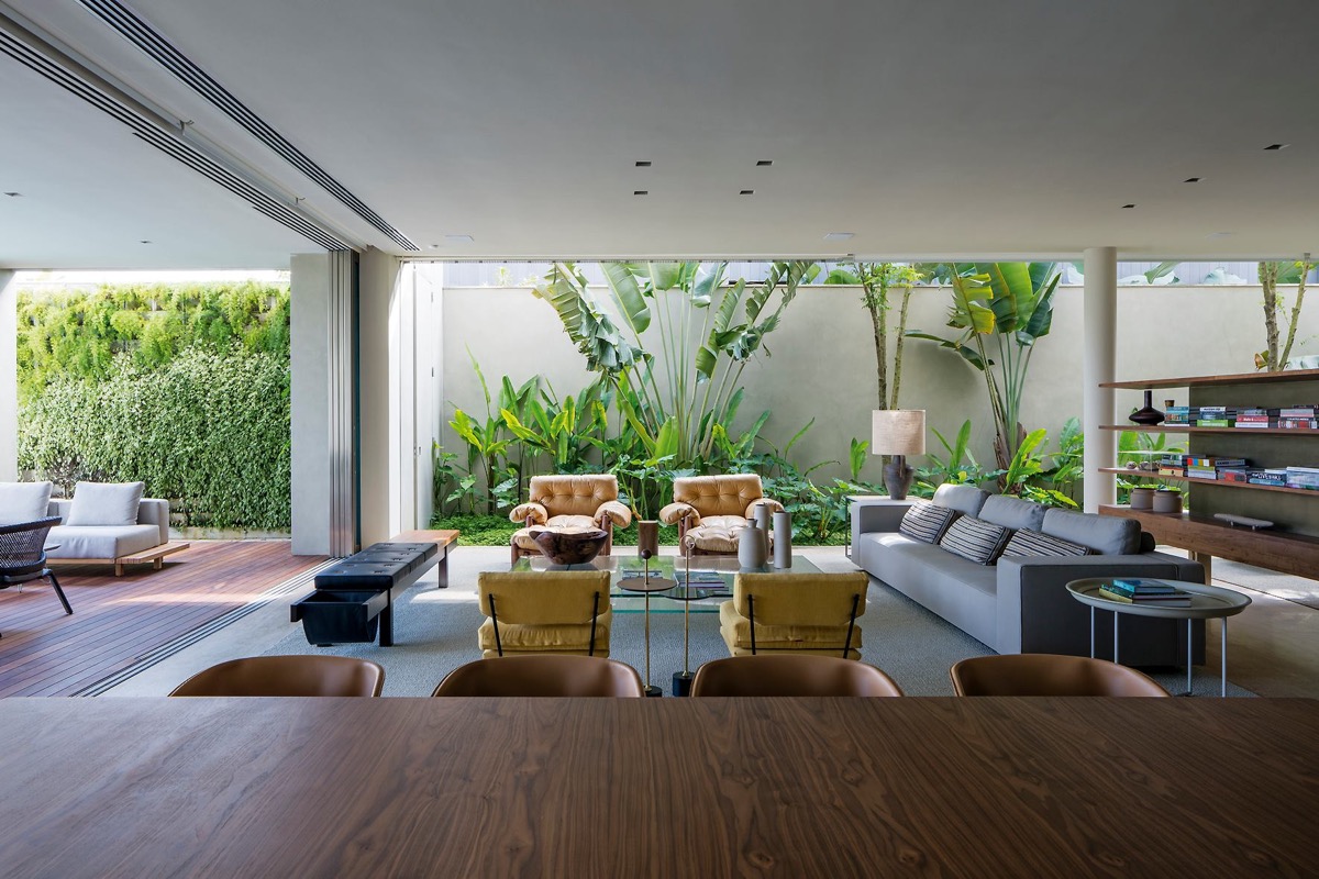 Ph&ograve;ng kh&aacute;ch sang trọng với tầm nh&igrave;n m&aacute;t mắt ra s&acirc;n vườn nơi h&ocirc;ng nh&agrave;. Cặp ghế b&agrave;nh t&ocirc;ng v&agrave;ng đồng nổi bật tr&ecirc;n nền xanh l&aacute; c&acirc;y.