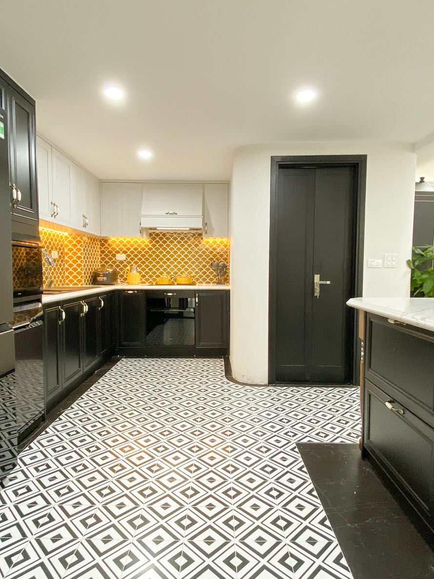 Backsplash ốp gạch họa tiết vảy c&aacute; t&ocirc;ng m&agrave;u v&agrave;ng s&aacute;ng b&oacute;ng tạo điểm nhấn ấn tượng tr&ecirc;n ph&ocirc;ng nền m&agrave;u đen - trắng chủ đạo.