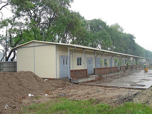 hình ảnh dãy nhà tạm dưới tán cây, bên cạnh là mô đất lớn