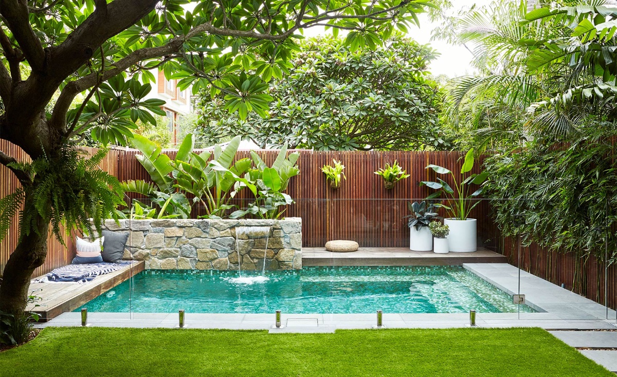 Luống c&acirc;y lớn bằng đ&aacute; tự nhi&ecirc;n tạo điểm nhấn trang tr&iacute; ấn tượng cho khu vực hồ bơi nơi s&acirc;n sau nh&agrave;. Gia chủ l&agrave;m th&ecirc;m lan can k&iacute;nh cường lực trong suốt vừa th&ocirc;ng tho&aacute;ng, sang trọng vừa đảm bảo an to&agrave;n cho trẻ nhỏ.