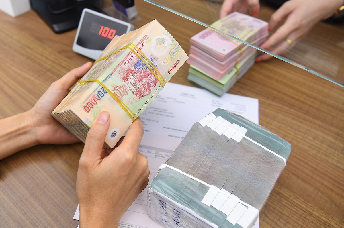 Nh&acirc;n vi&ecirc;n một ng&acirc;n h&agrave;ng tại H&agrave; Nội đang thực hiện giao dịch với kh&aacute;ch h&agrave;ng. Ảnh: Giang Huy