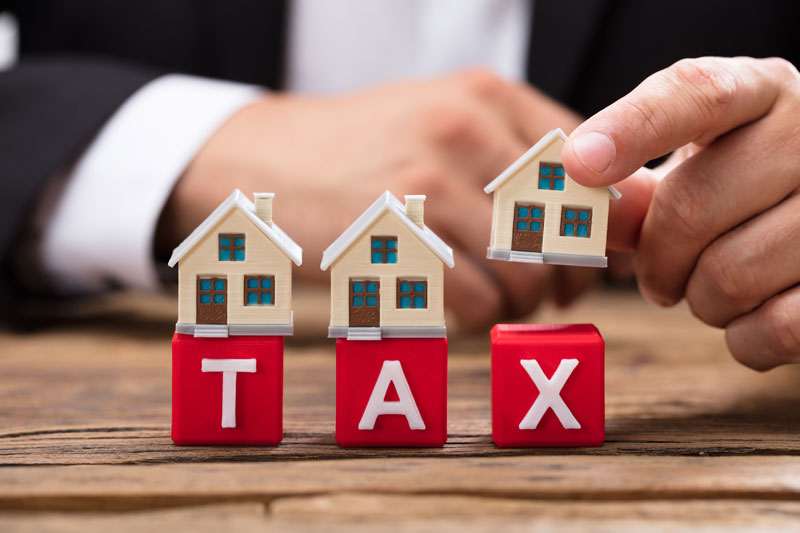 cận cảnh mô hình ngôi nhà và dòng chữ TAX màu đỏ minh họa cho thuế phí khi sang tên sổ hồng chung cư