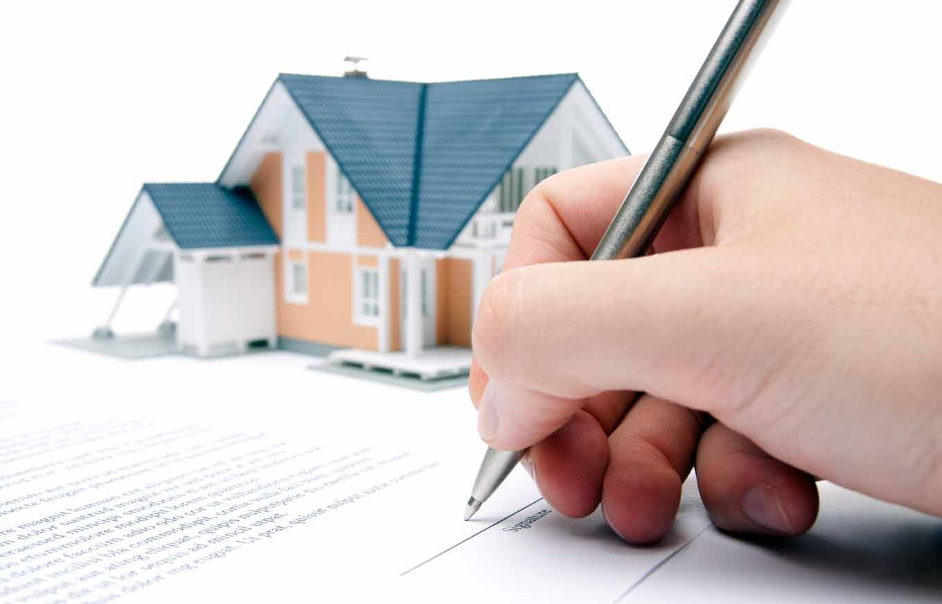 cận cảnh ký hợp đồng bên cạnh mô hình ngôi nhà minh họa cho thủ tục tách sổ đỏ
