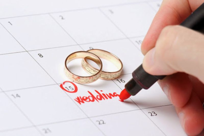 cặp nhẫn cưới đặt ở ô lịch có chữ wedding màu đỏ