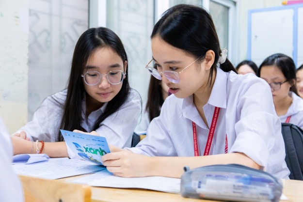 A group of girls looking at a piece of paper  Description automatically generated