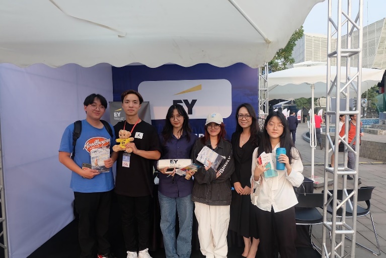 A group of people standing in front of a white tent  Description automatically generated