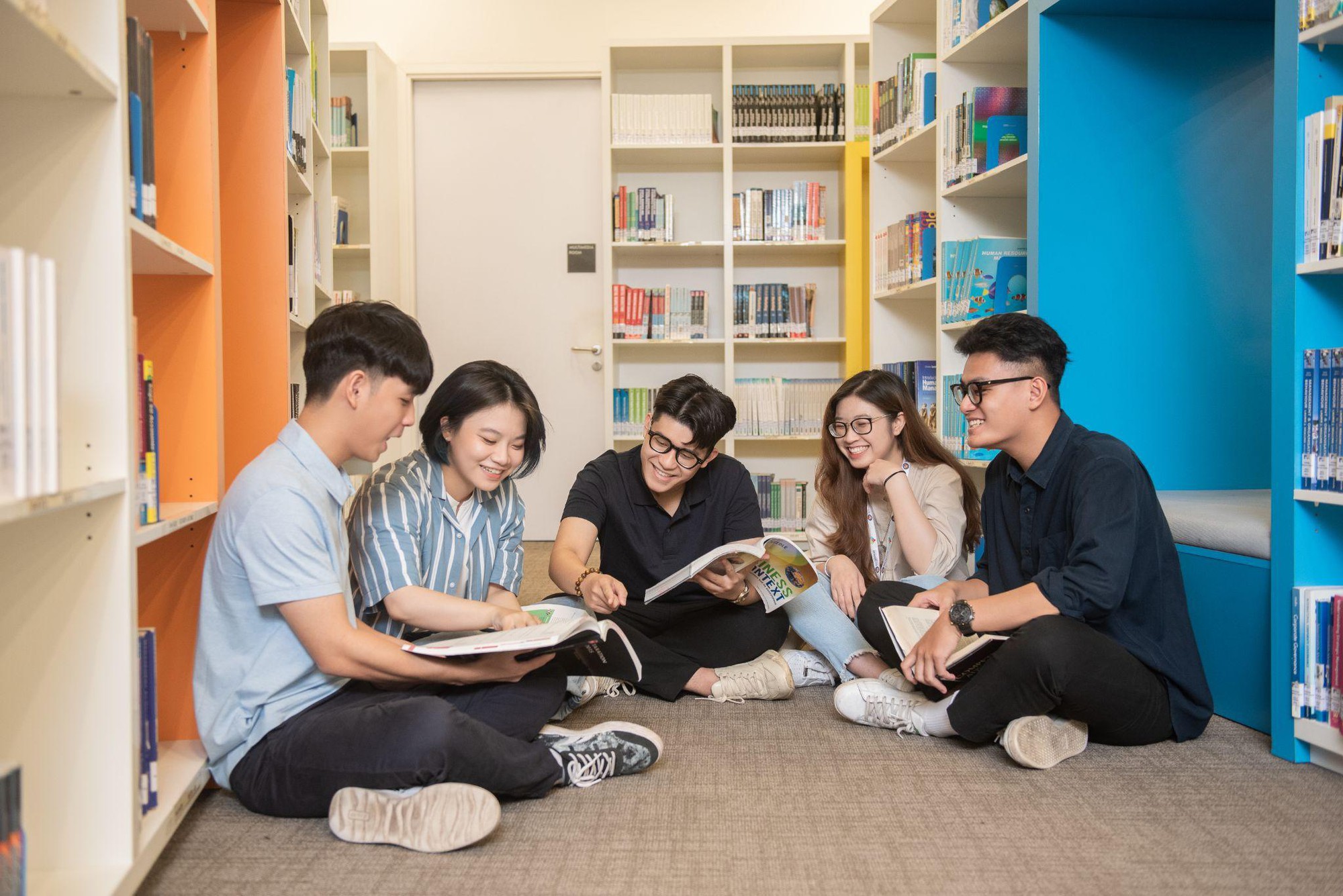 A group of people sitting on the floor reading books  Description automatically generated