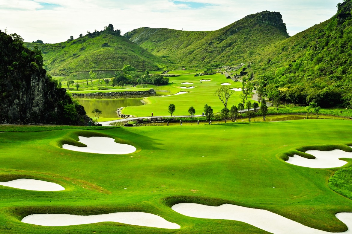 Legend Valley Country Club: Từ vùng đầm lầy hoang sơ đến 'thiên đường golf' giữa lòng Ninh Bình- Ảnh 5. A golf course with water in the middle AI-generated content may be incorrect.