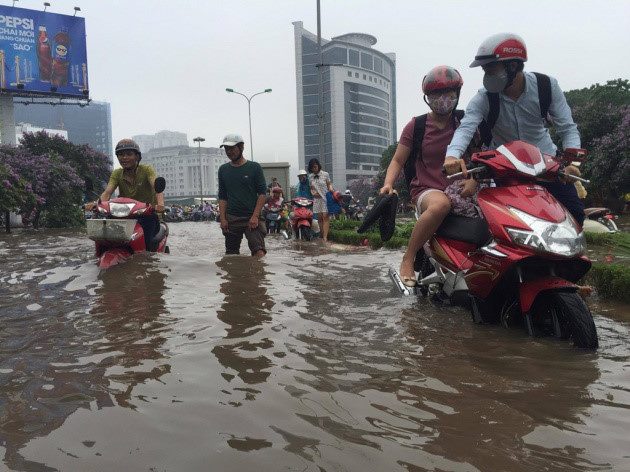 Người d&acirc;n d&ugrave;ng xe m&aacute;y để lội nước tr&ecirc;n đường ngập