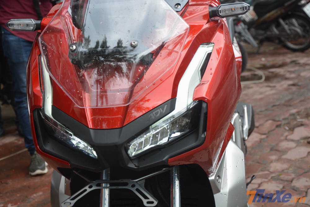 Cận cảnh mặt tiền của Honda ADV 150. Xe có đèn pha LED, dải đèn LED chiếu sáng ban ngày cỡ lớn và kính chắn gió có thể điều chỉnh Cận cảnh mặt tiền của Honda ADV 150. Xe có đèn pha LED, dải đèn LED chiếu sáng ban ngày cỡ lớn và kính chắn gió có thể điều chỉnh