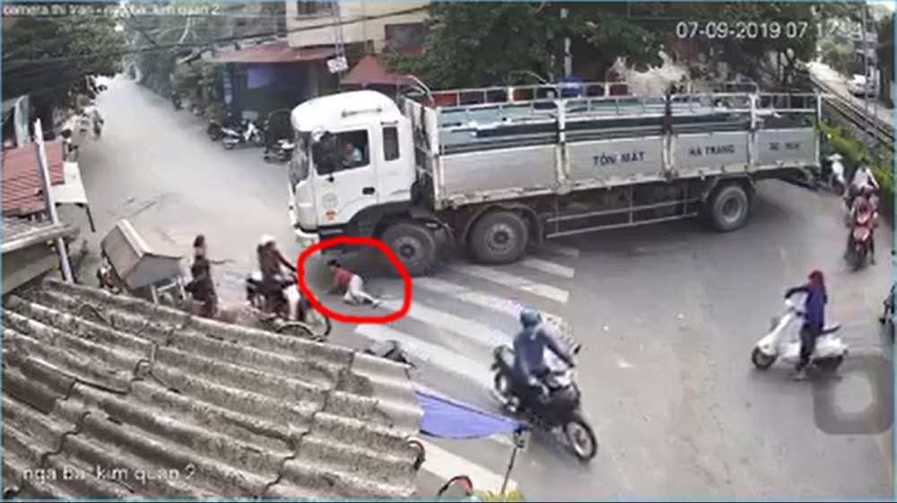 Người phụ nữ nằm dưới gầm xe, ngay cạnh bánh trước Người phụ nữ nằm dưới gầm xe, ngay cạnh bánh trước