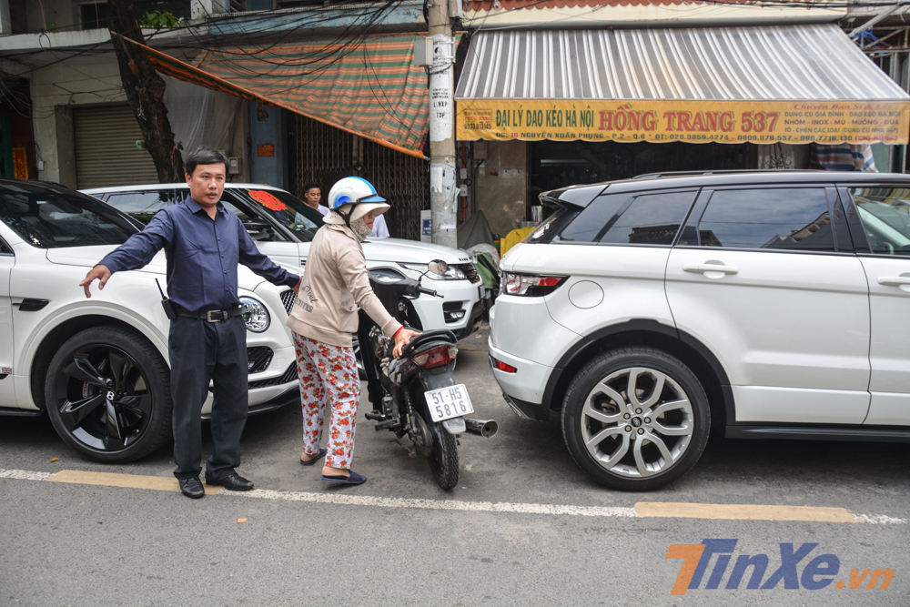 Một người dân cố gắng đẩy chiếc Honda Wave của mình vào trong nhà nhưng đội vệ sĩ giải thích và mong cô thông cảm chịu khó để xe bên kia đường Một người dân cố gắng đẩy chiếc Honda Wave của mình vào trong nhà nhưng đội vệ sĩ giải thích và mong cô thông cảm chịu khó để xe bên kia đường