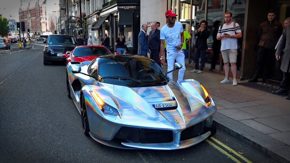 Pierre-Emerick Aubameyang đội n&oacute;n đỏ đứng b&ecirc;n cạnh Ferrari LaFerrari m&agrave;u cr&ocirc;m t&aacute;n sắc