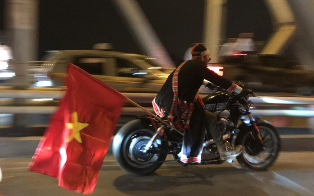 Biker với bộ đồ d&acirc;n tộc kh&ocirc;ng đội mũ bảo hiểm, chạy xe Harley-Davidson tr&ecirc;n cầu Chương Dương