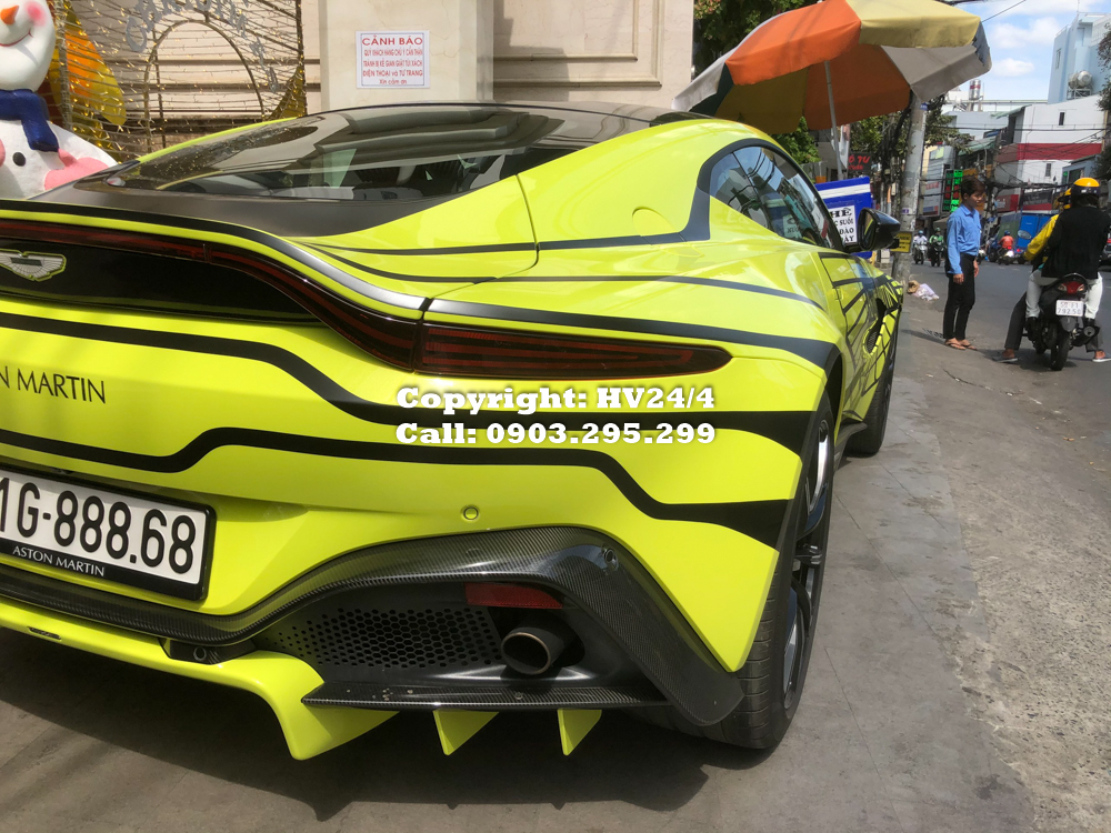 Dựa tr&ecirc;n m&agrave;u sơn v&agrave;ng Lime Essence nguy&ecirc;n bản của si&ecirc;u xe Aston Martin V8 Vantage 2018, doanh nh&acirc;n quận 12 nhờ những người thợ nước ngo&agrave;i v&agrave; cả S&agrave;i th&agrave;nh l&ecirc;n bộ tem mới cho xe với t&ocirc;ng m&agrave;u đen l&agrave;m chủ đạo.