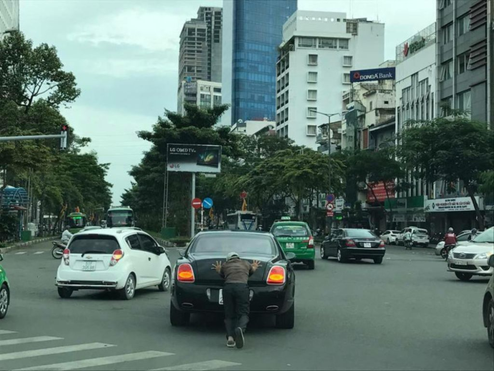 Một người đ&agrave;n &ocirc;ng đẩy chiếc xe si&ecirc;u sang Bentley Continental Flying Spur tại S&agrave;i th&agrave;nh