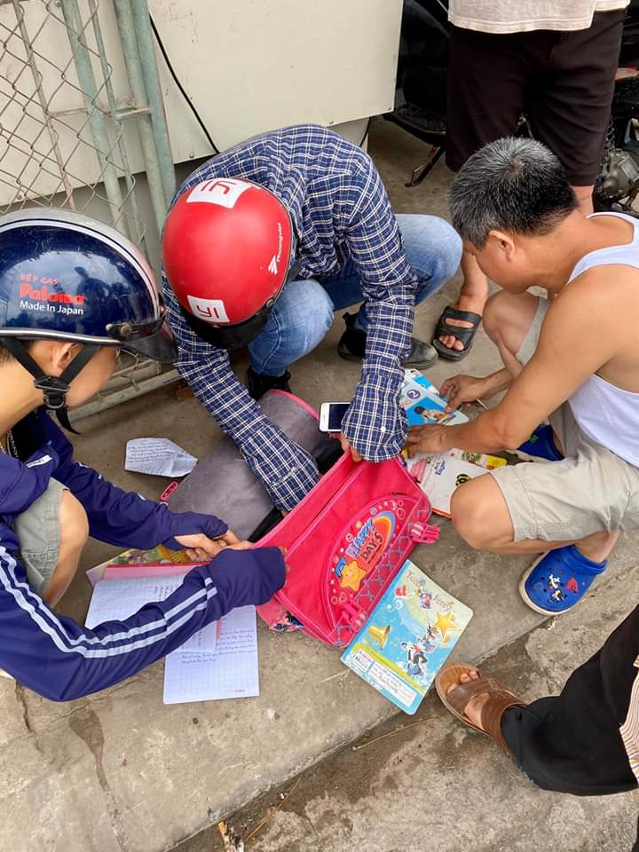 Người dân xem tập vở của em học sinh gặp nạn để thông báo người thân đến bệnh viện