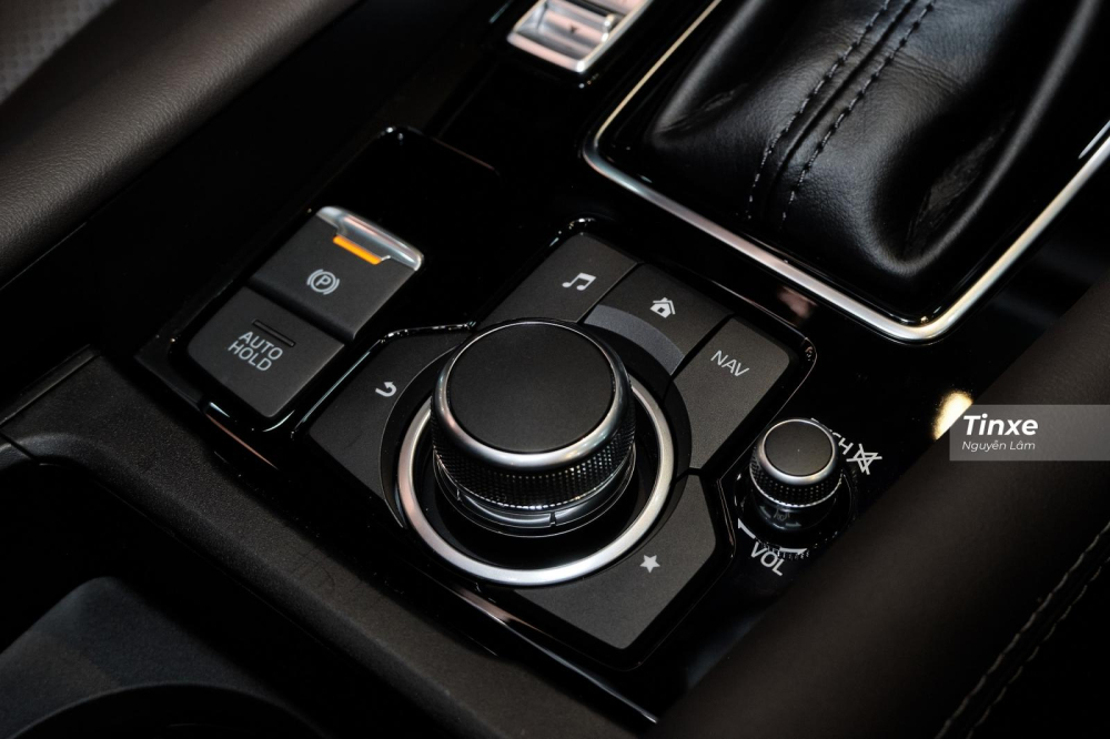 Phía bên dưới là núm vặn điều chỉnh hệ thống giải trí thường thấy của Mazda, bên cạnh là phanh đỗ điên tử có đi kèm chức năng Auto Hold