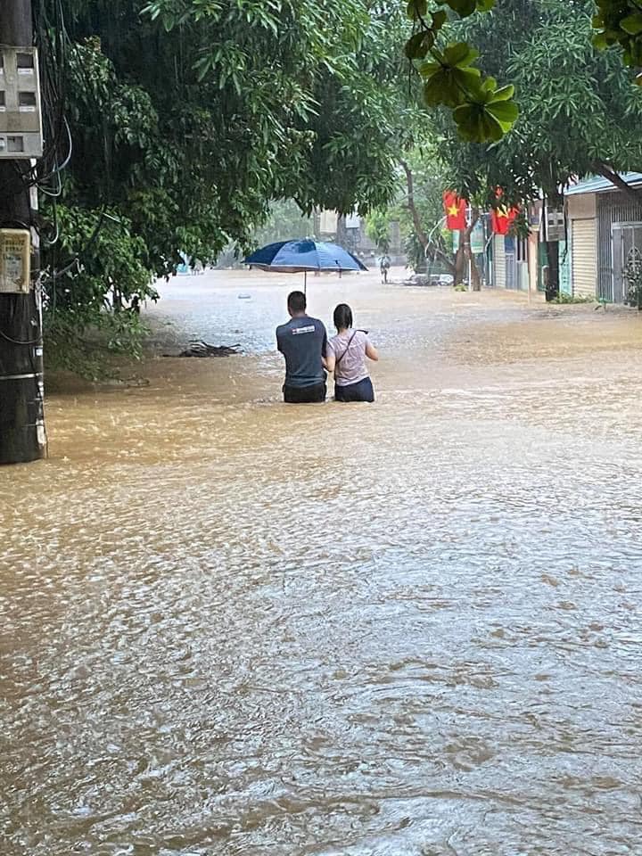 Người dân lội bì bòm trên con đường đã bị biến thành sông