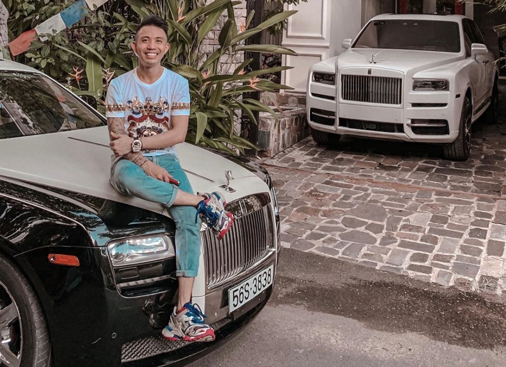 Minh Nhựa ngồi trước đầu xe Rolls-Royce Ghost v&agrave; ph&iacute;a chỗ đỗ xe ở garage ch&iacute;nh l&agrave; Rolls-Royce Cullinan. Chỗ n&agrave;y hay được Minh Nhựa đậu Pagani Huayra