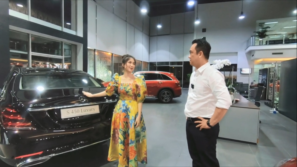 Ho&agrave; Minzy c&ugrave;ng nh&acirc;n vi&ecirc;n b&aacute;n h&agrave;ng của Mercedes-Benz b&ecirc;n cạnh chiếc xe sang Mercedes-Benz S450L Luxury m&agrave;u đỏ Ruby