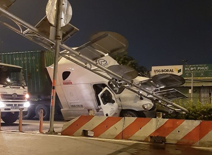 Phần đầu xe container nghiêng về một bên sau khi leo lên dải phân cách và húc đổ cột biển báo giao thông