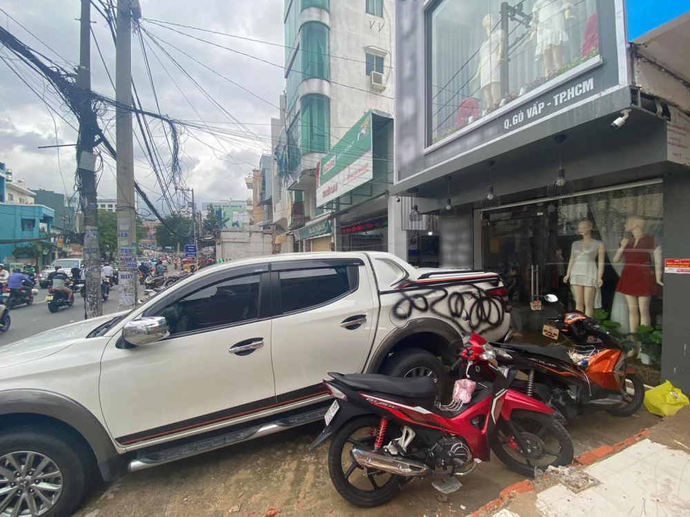 Chiếc ô tô bán tải Mitsubishi Triton đỗ chắn trước cửa của một cửa hàng bán quần áo