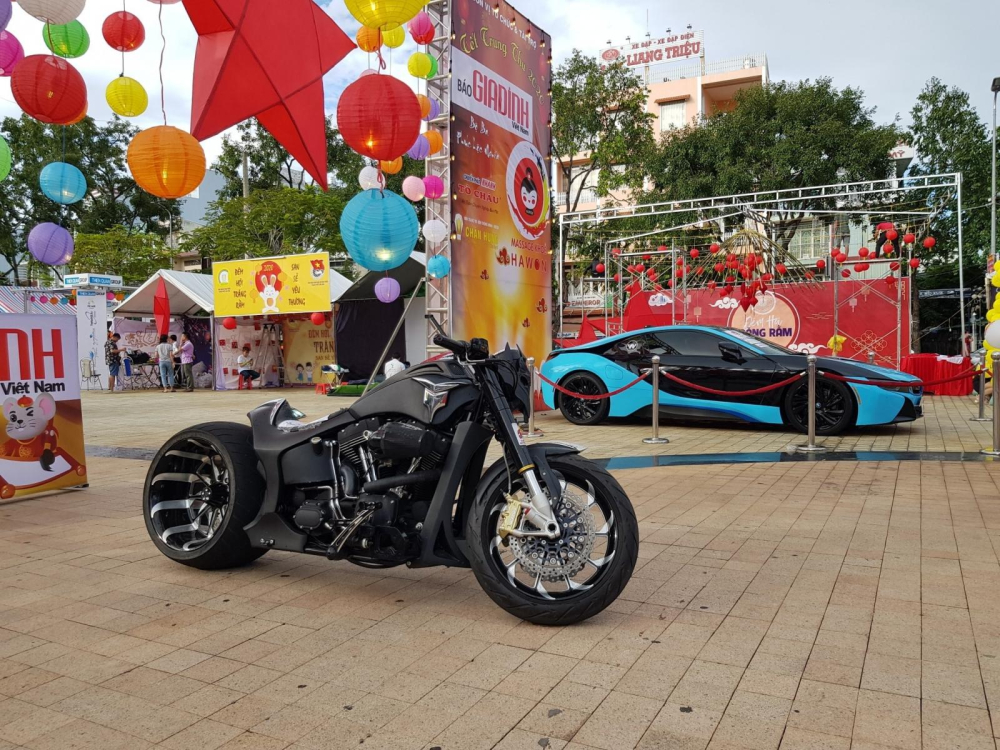 Chiếc xe mô tô phân khối lớn và phía xa là BMW i8 phối 2 tông màu xanh ngọc và đen