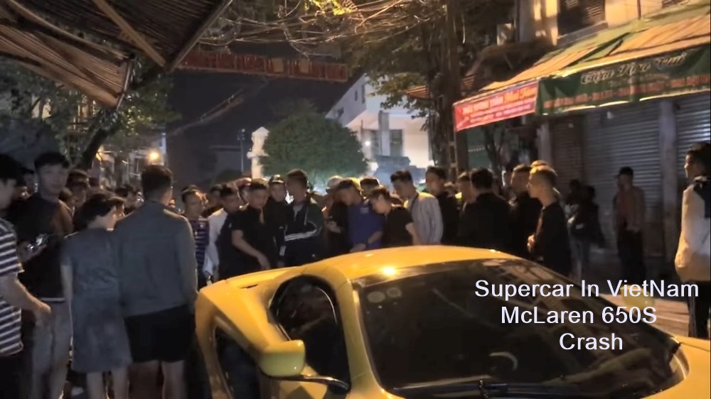 Người dân vây quanh chiếc siêu xe McLaren sau khi bị đoàn đua xe tông vào phía sau
