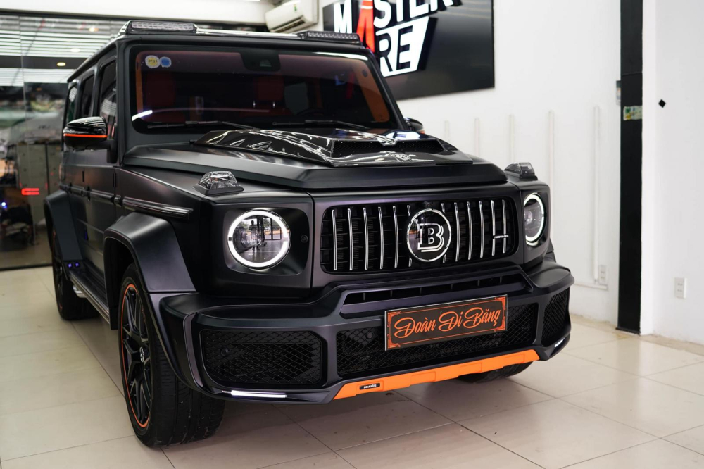 Chiếc SUV hạng sang Mercedes-AMG G63 Edition 1 được trang trí thêm các sọc đề-can màu cam đi kèm bộ áo đen nhám của xe. Xe được trang bị thêm body kit của Brabus