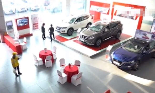 Anh chàng shipper mặc áo đồng phục màu vàng đến đại lý Nissan để giao đồ ăn