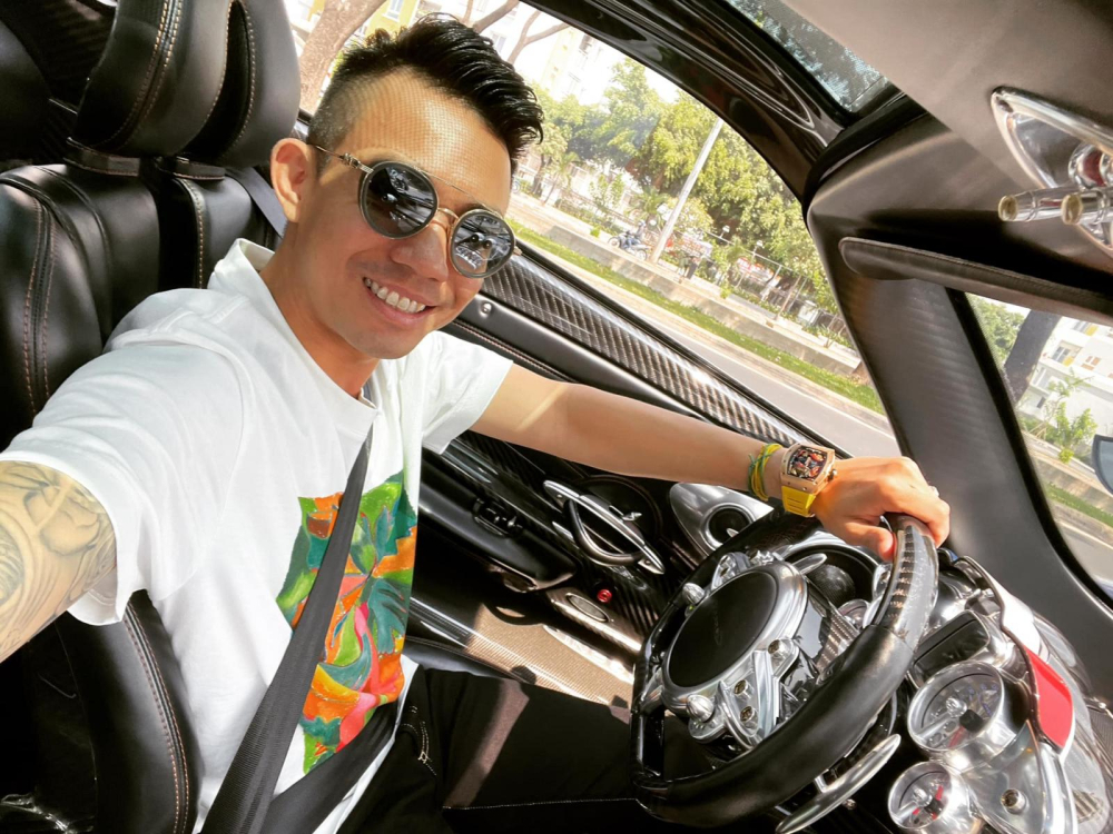 Minh Nhựa cầm l&aacute;i Pagani Huayra với trang phục &aacute;o thun trắng, quần jeans đen, tay tr&aacute;i đeo Richard Mille Dragon Jackie Chan Tourbillon chỉ sản xuất đ&uacute;ng 3 chiếc tr&ecirc;n thế giới 