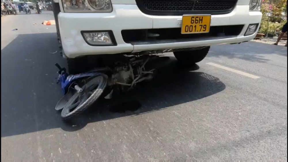 Chiếc xe máy nằm dưới gầm xe ben
