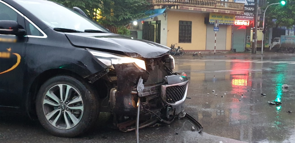 Chiếc xe Kia Sedona vỡ nát phần cản va trước, lưới tản nhiệt bung ra khỏi xe, đèn pha bể