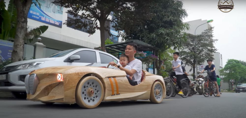 Anh Đạo điều khiển chiếc ô tô bằng gỗ đưa con đi mẫu giáo