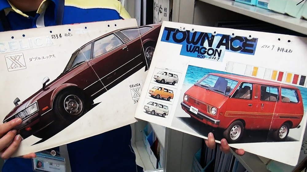 Cô Hamaguchi cầm trên tay catalogue của 2 mẫu xe Toyota Celica và TownAce